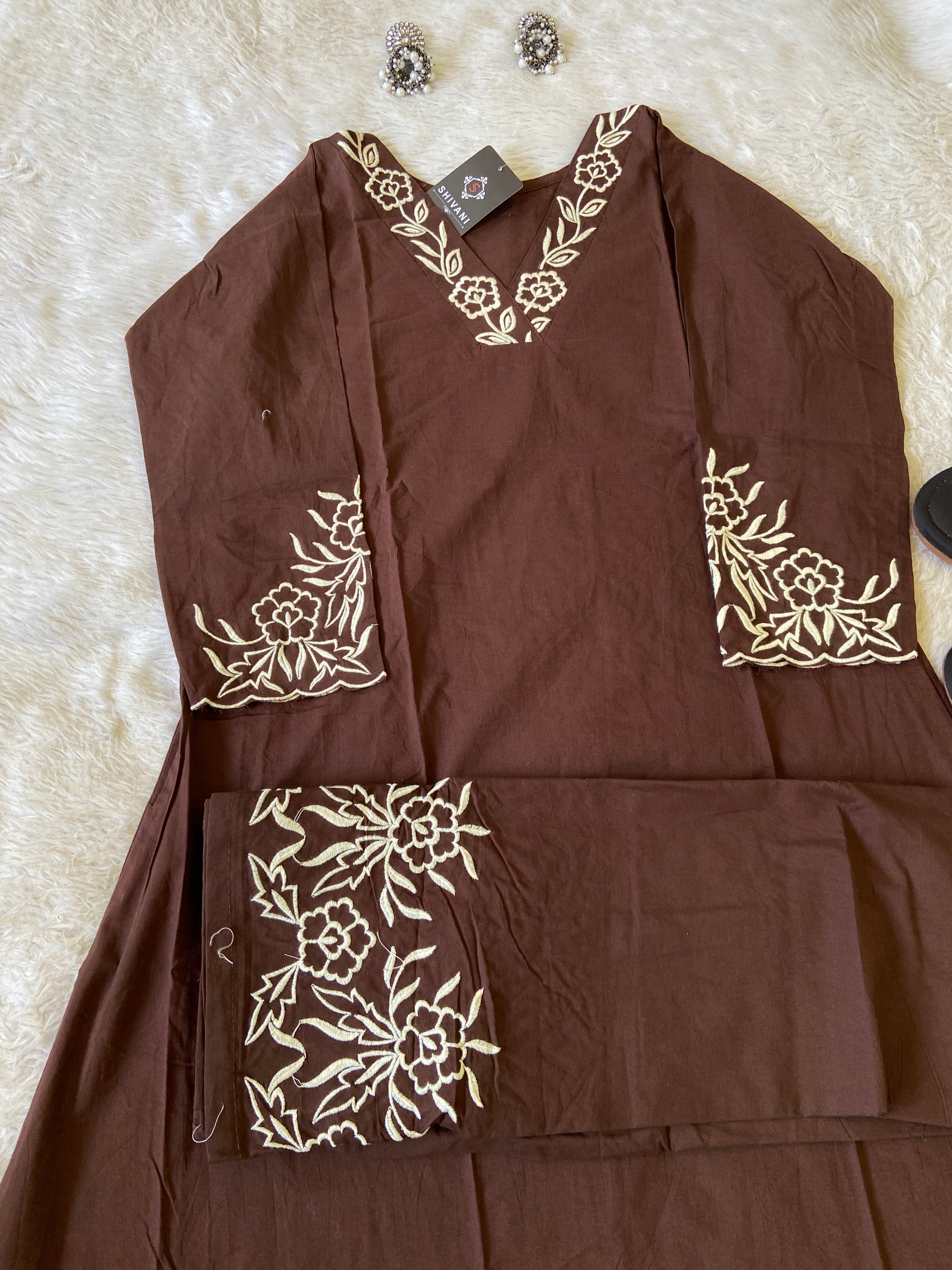 Brown garment with white floral embroidery on a white fur surface
