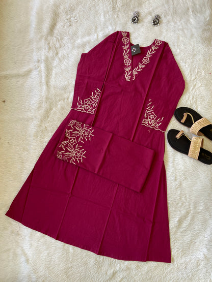 Red dress with white floral embroidery on a textured surface