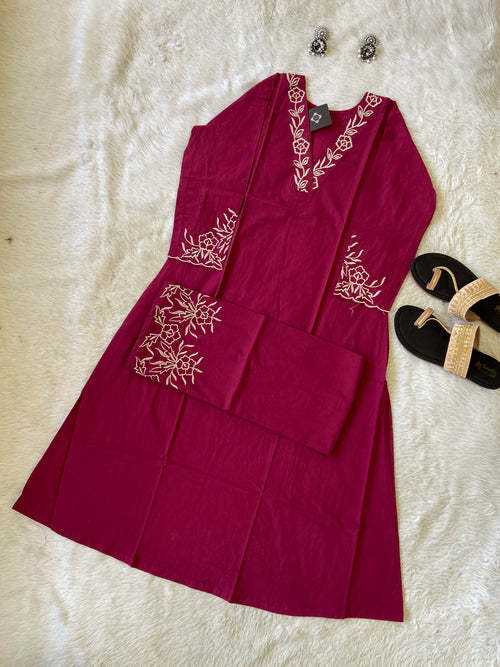 Red dress with white floral embroidery on a textured surface