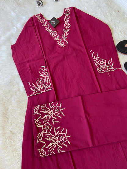 Maroon fabric with white floral embroidery on a textured surface