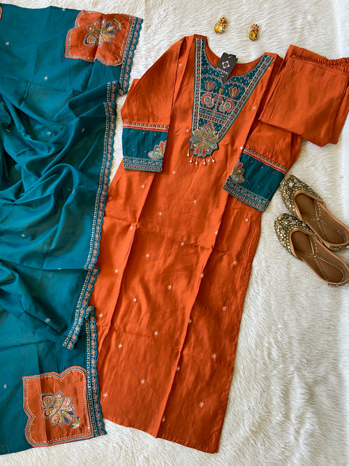 Traditional orange and blue saree with intricate patterns on a textured white surface.