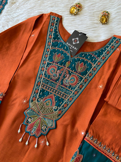 Brown traditional outfit with intricate blue and gold embroidery on a white fabric background