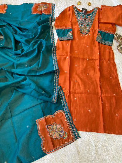 Orange and blue traditional outfit with intricate embroidery on a white surface