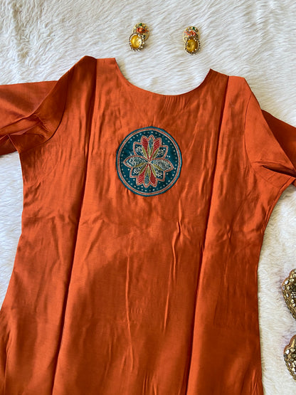 Orange fabric with a decorative patch on a white surface