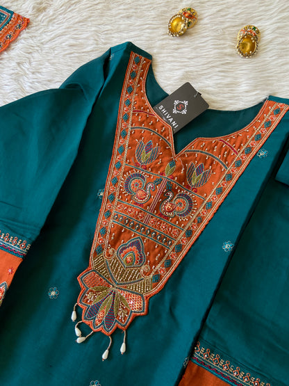 Teal fabric with intricate orange embroidery on a white surface