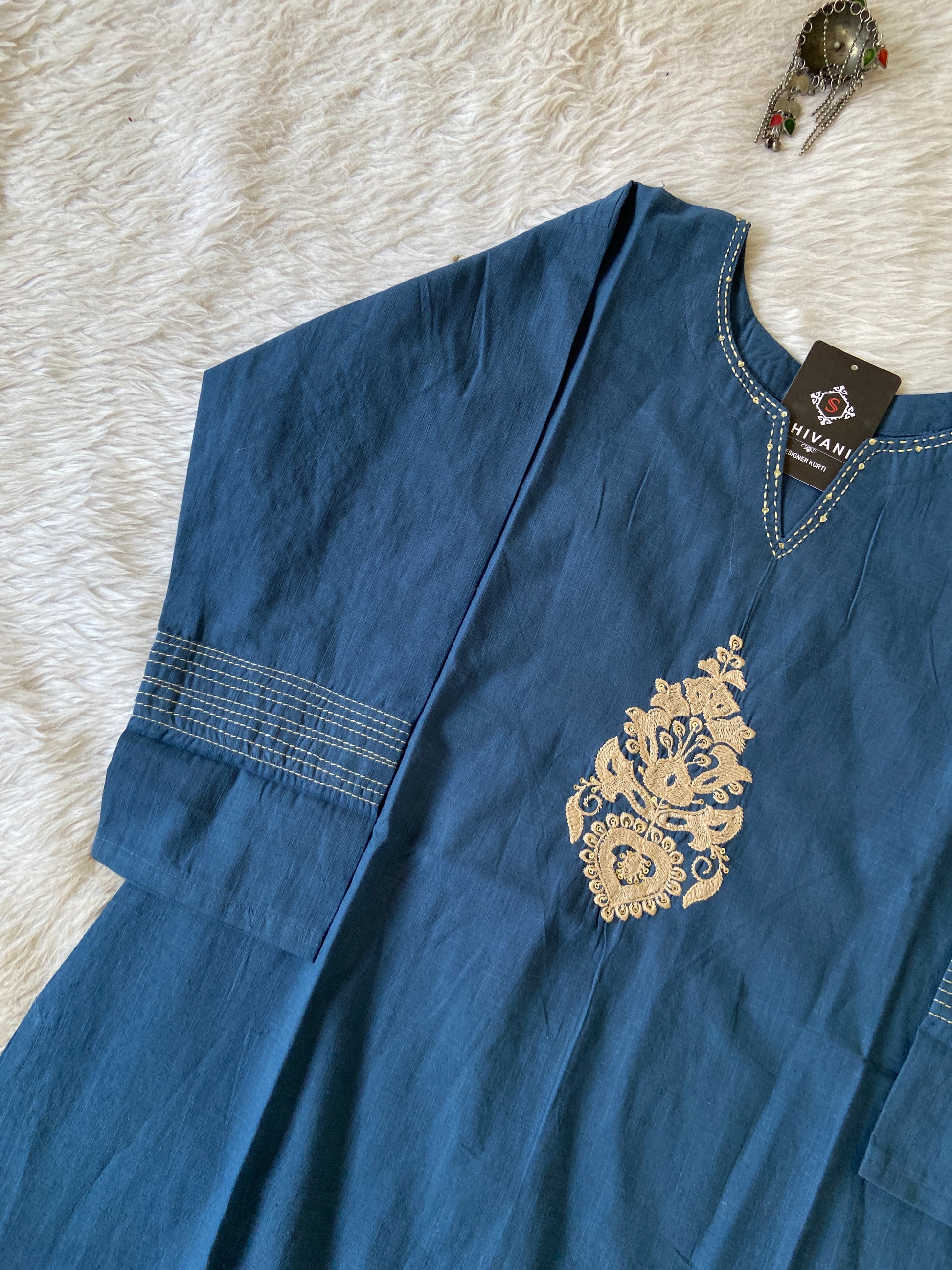 Blue shirt with gold embroidery on a white textured surface