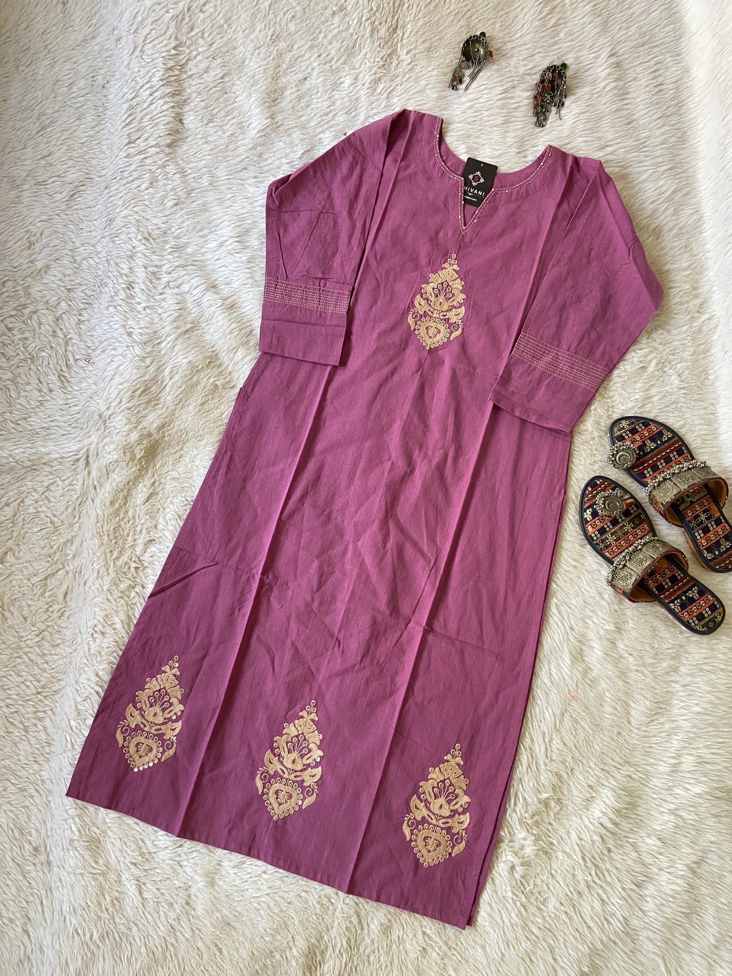 Purple dress with gold embroidery on a white fur surface