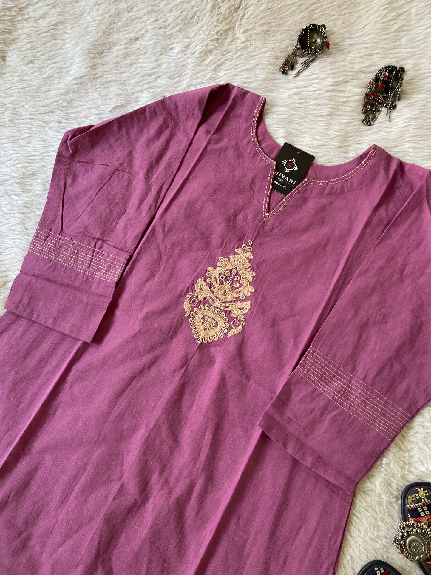 Purple shirt with gold embroidery on a textured surface
