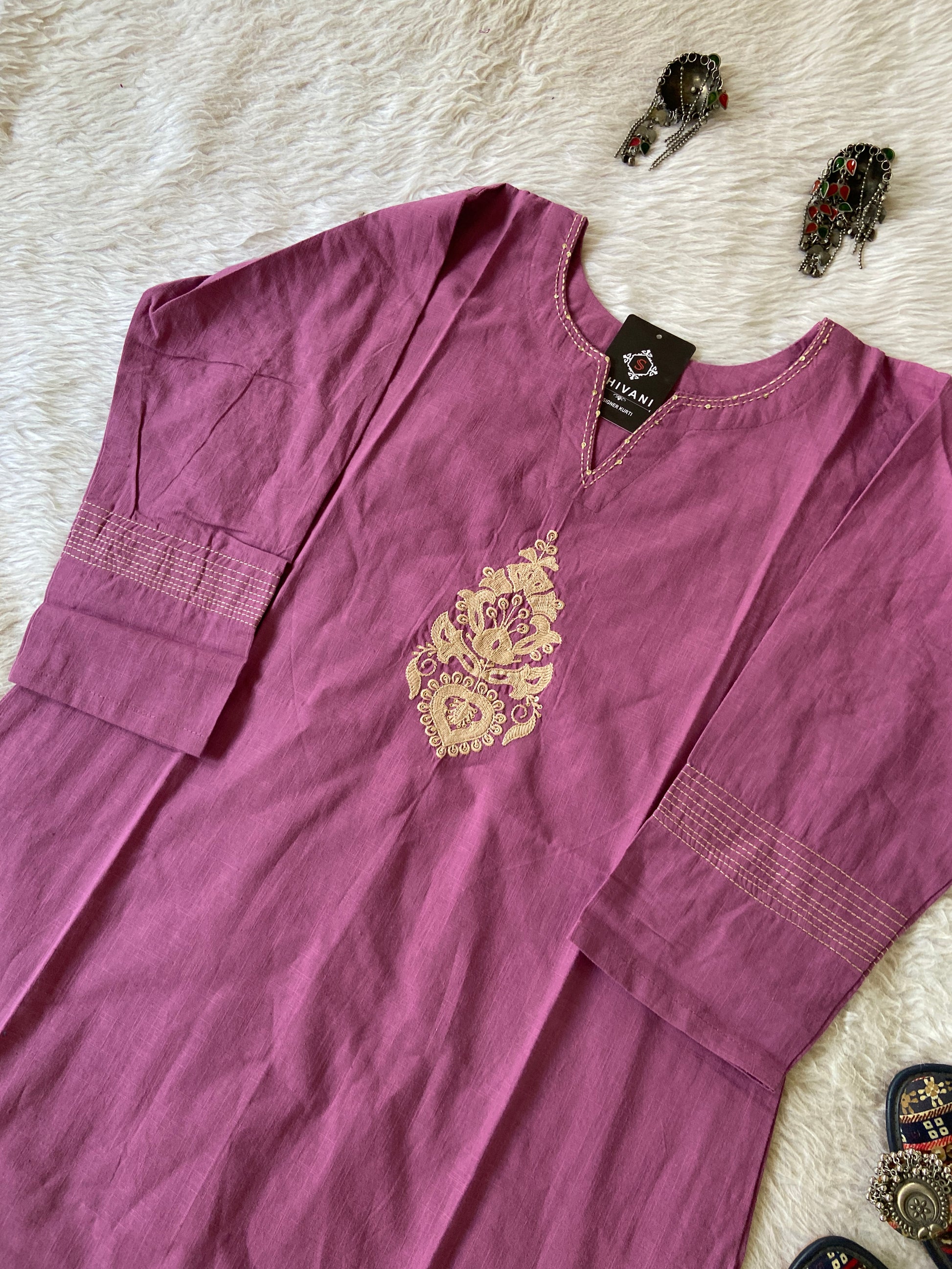 Purple shirt with gold embroidery on a textured surface