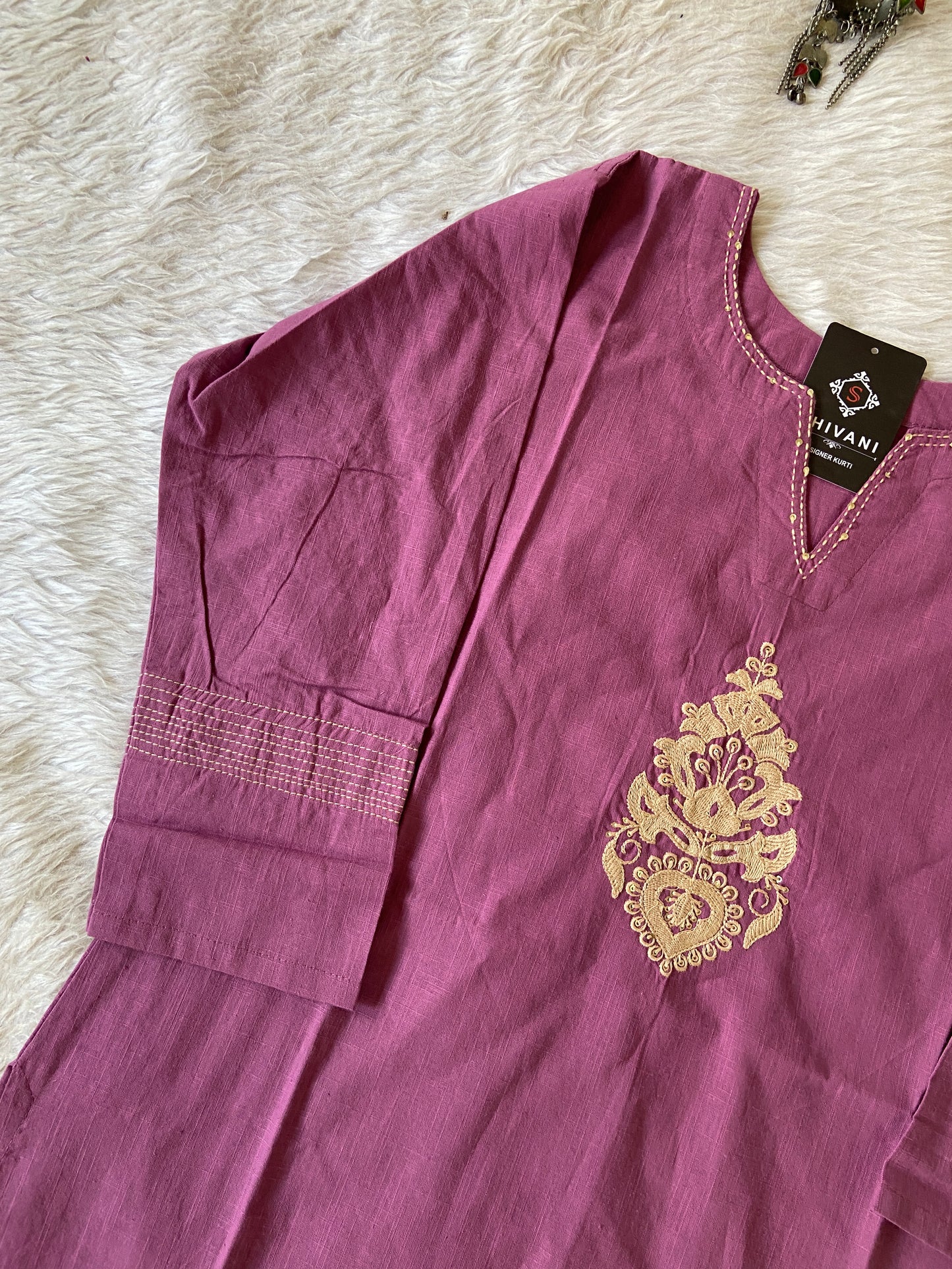Purple garment with gold embroidery on a white fluffy surface