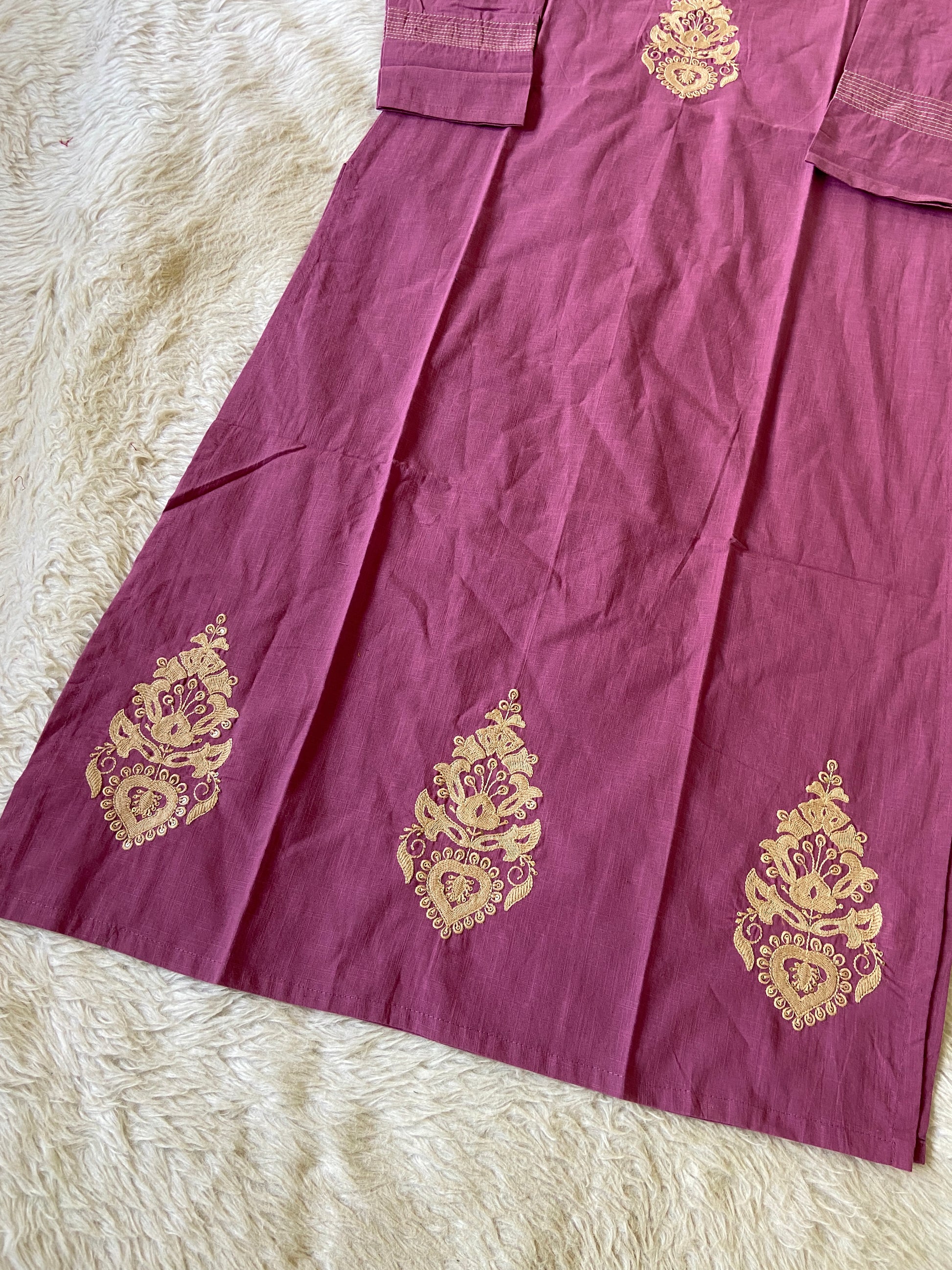 Purple fabric with gold embroidery on a white surface