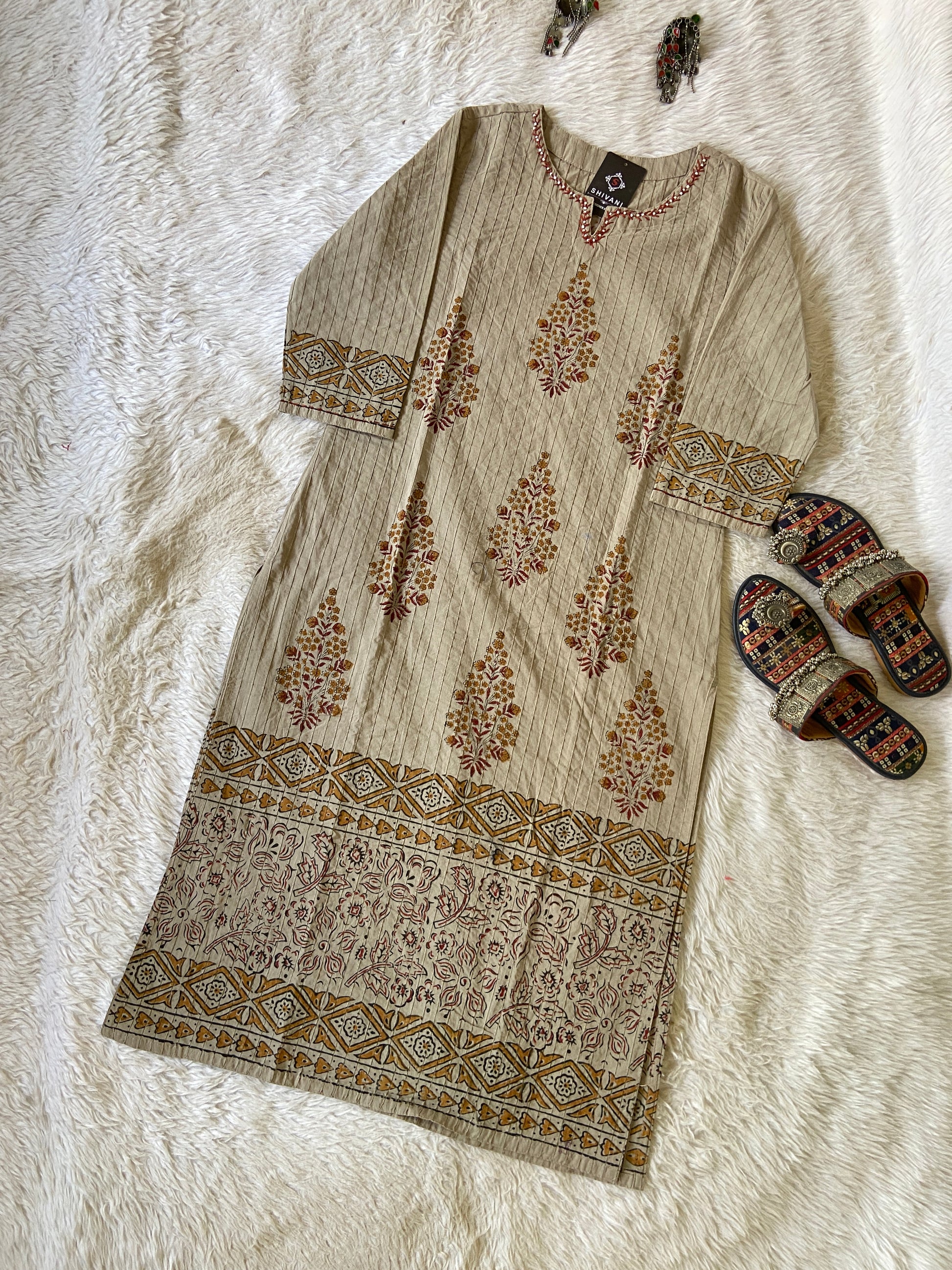 Beige kurta with floral patterns on a white textured surface