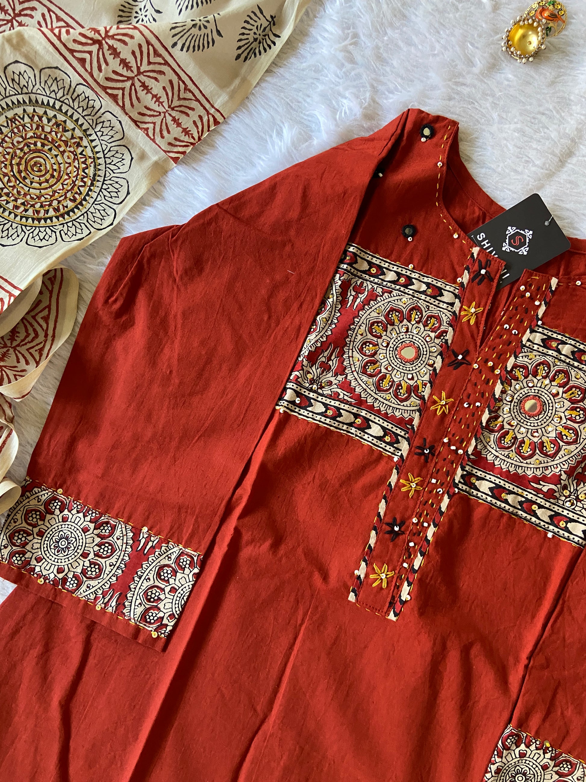 Red fabric with intricate gold patterns on a white surface