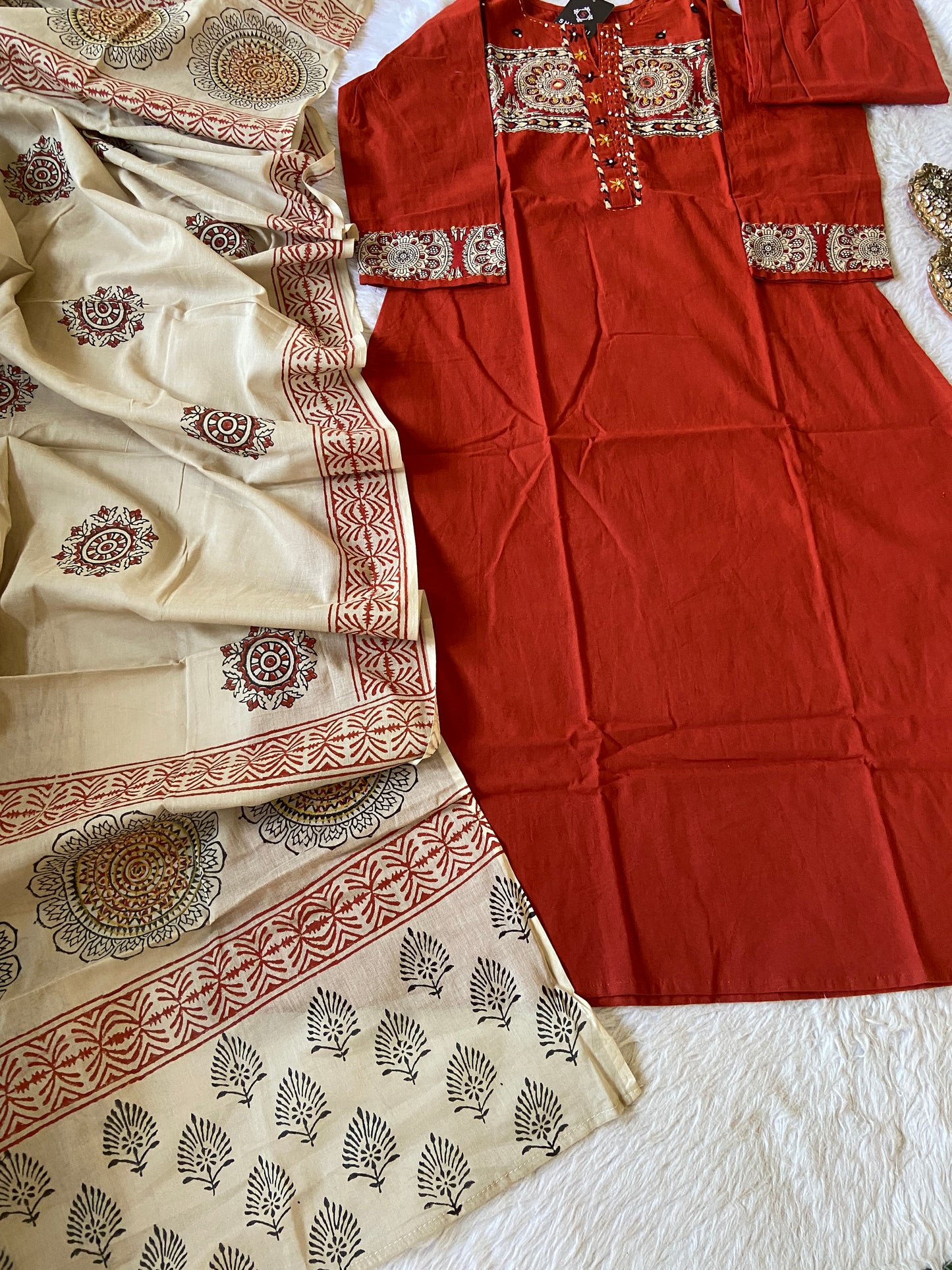 Red traditional outfit with beige saree featuring intricate patterns on a white surface