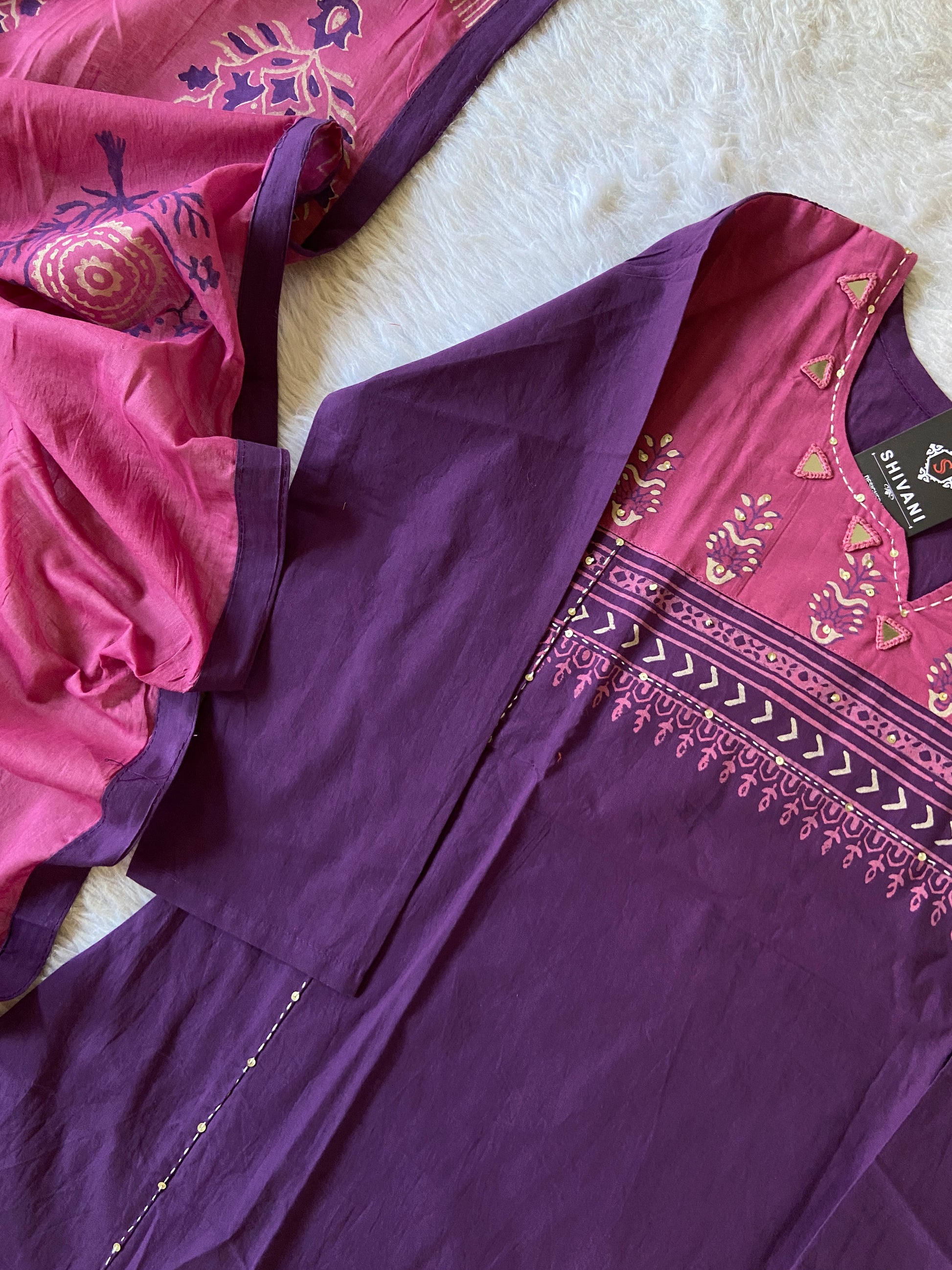 Purple and pink traditional fabric with intricate patterns on a white surface
