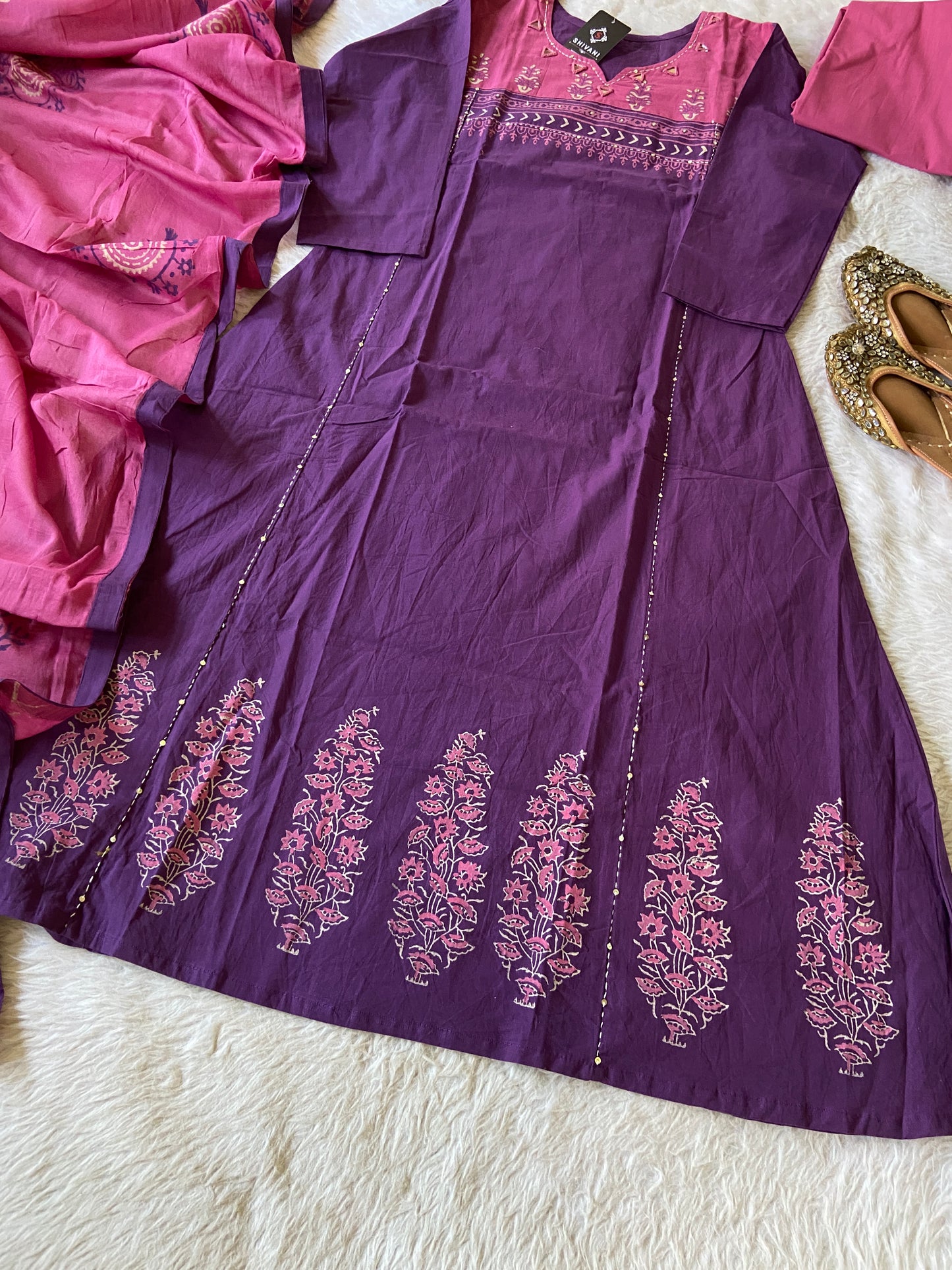 Purple traditional outfit with floral embroidery on a white surface