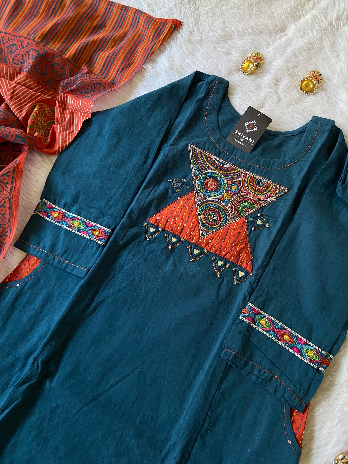 Blue embroidered garment with colorful patterns on a textured surface
