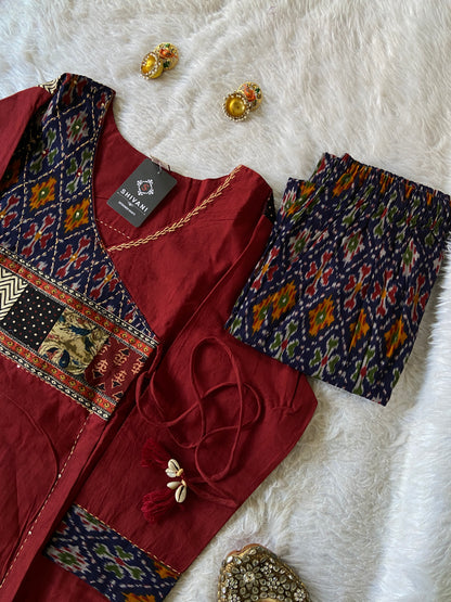 Traditional outfit with embroidered top, pants, and earrings on a white fabric background