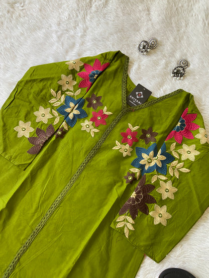 Green embroidered garment with colorful flowers on a white surface