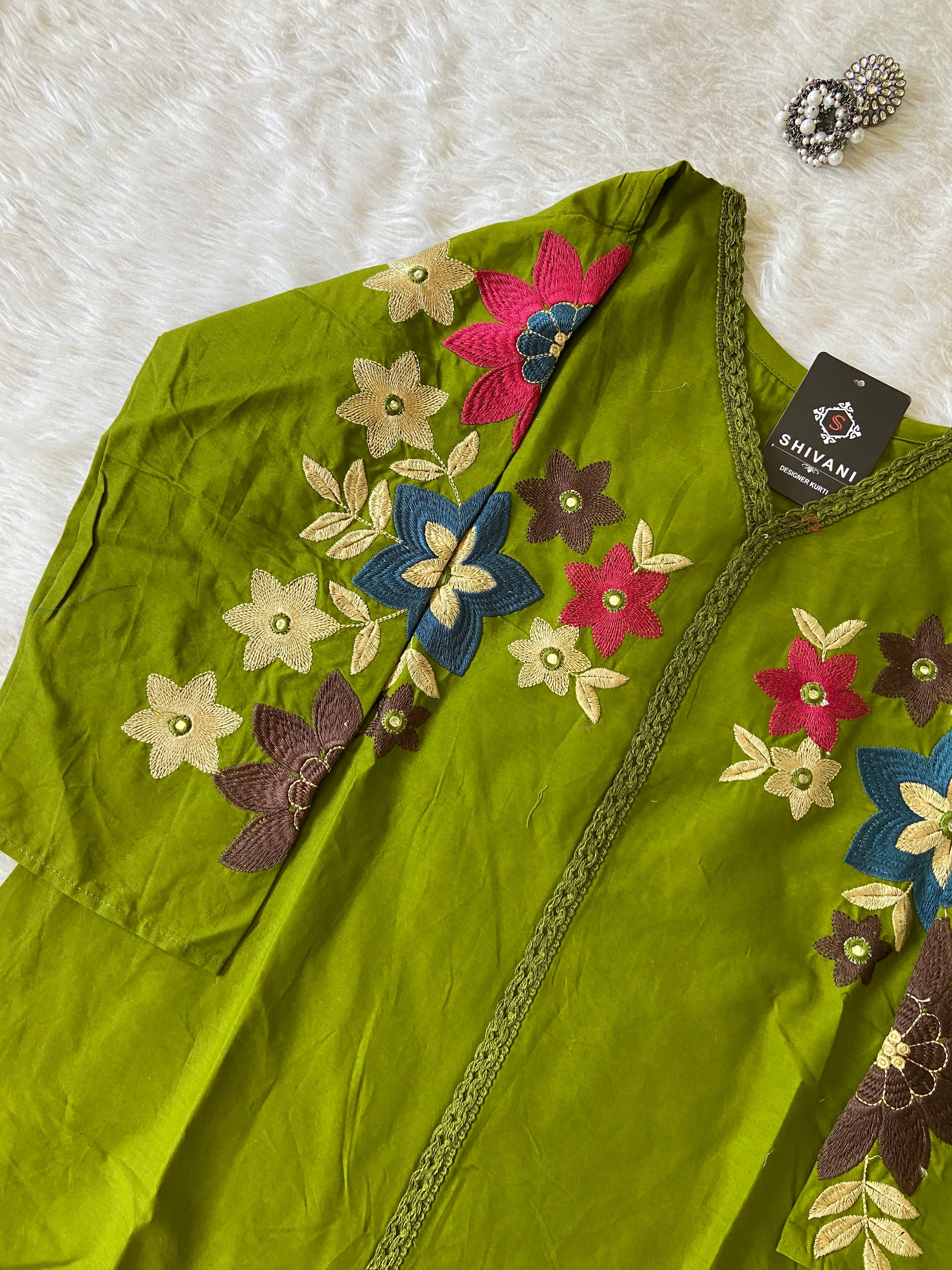 Green fabric with floral embroidery on a white surface