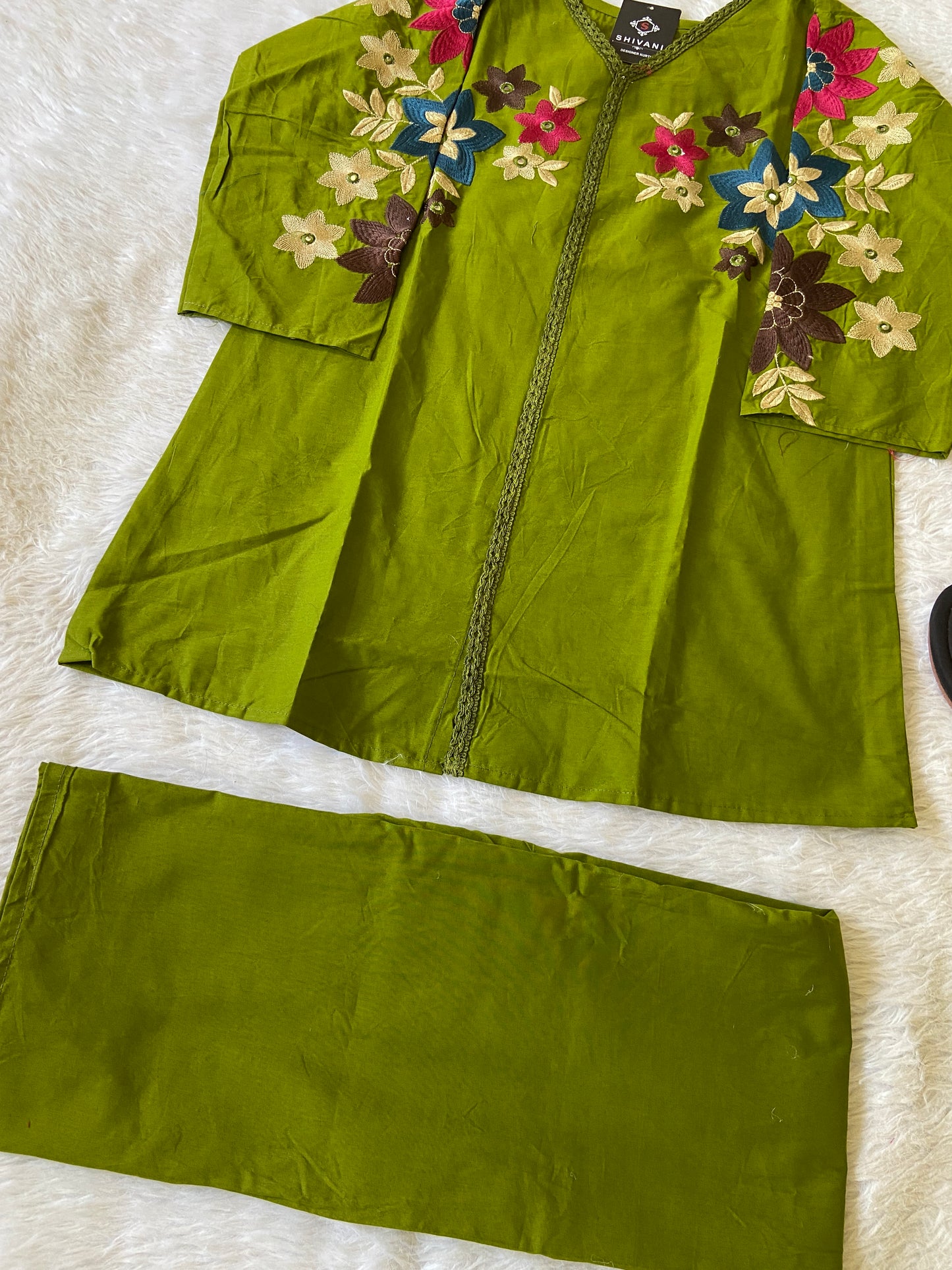 Green embroidered garment on a white surface