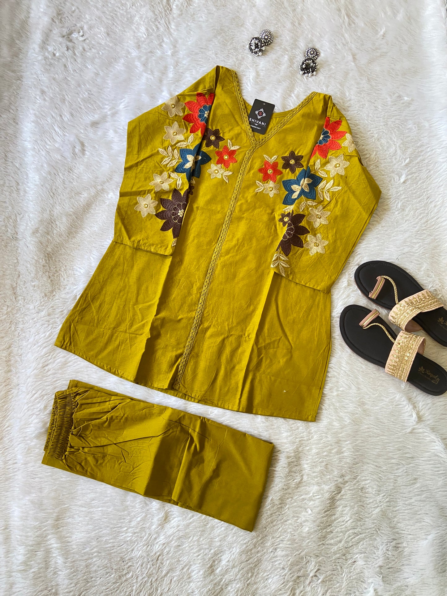 Yellow outfit with floral embroidery on a white textured surface