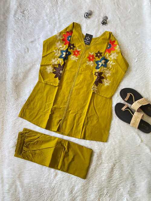 Yellow outfit with floral embroidery on a white textured surface