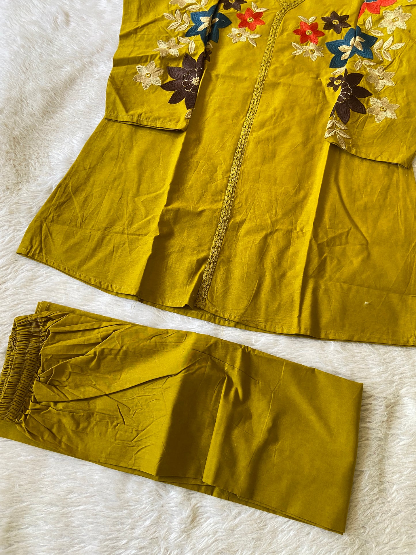 Mustard yellow fabric with floral embroidery on a white surface