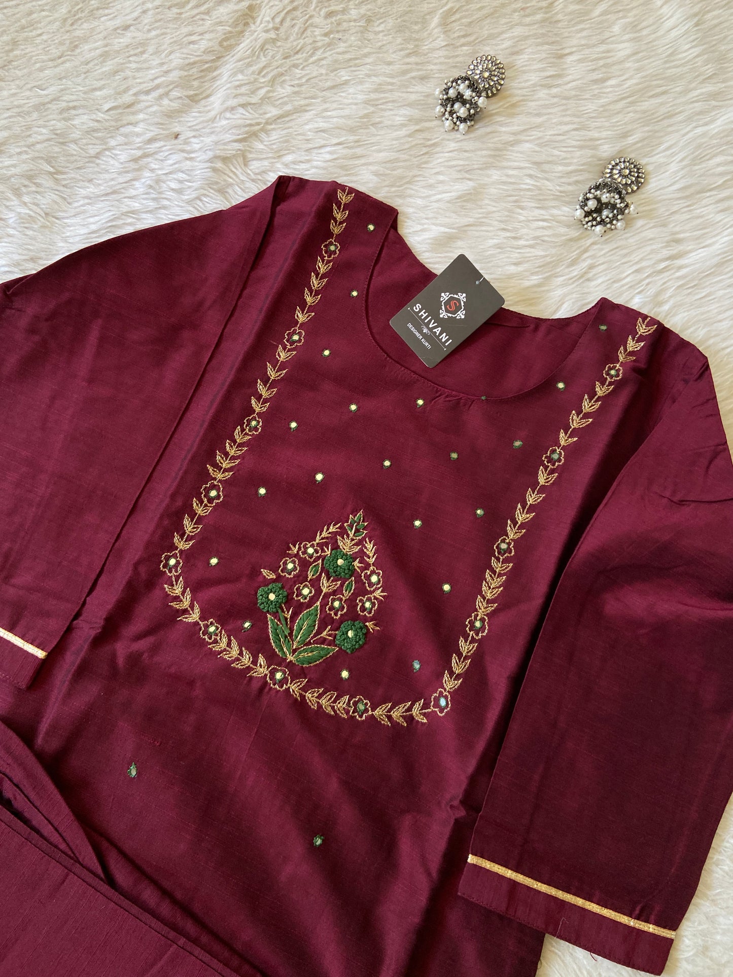 Maroon outfit with gold embroidery on a white surface