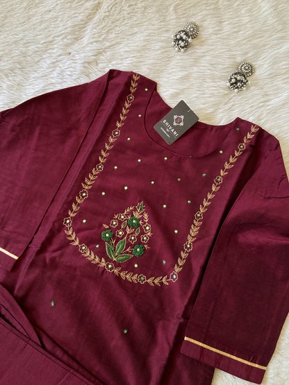 Maroon outfit with gold embroidery on a white surface