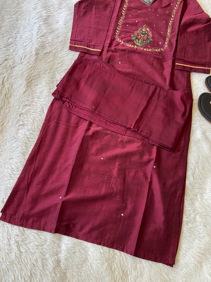 Maroon traditional outfit with gold embroidery on a white surface