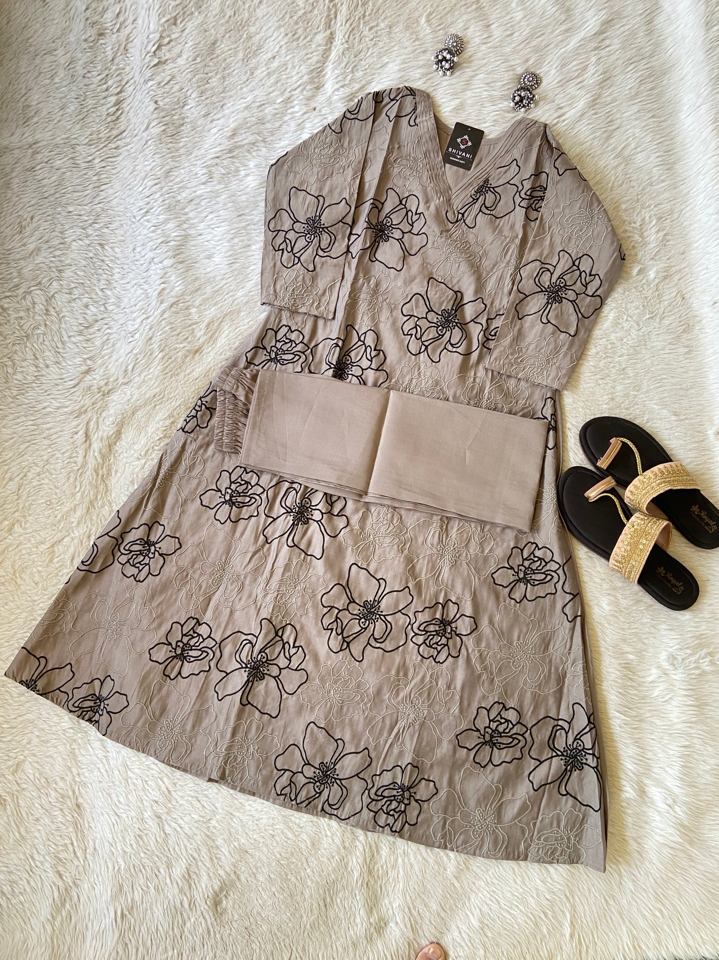 Floral-patterned dress on a white fur surface with sandals and a hair clip.
