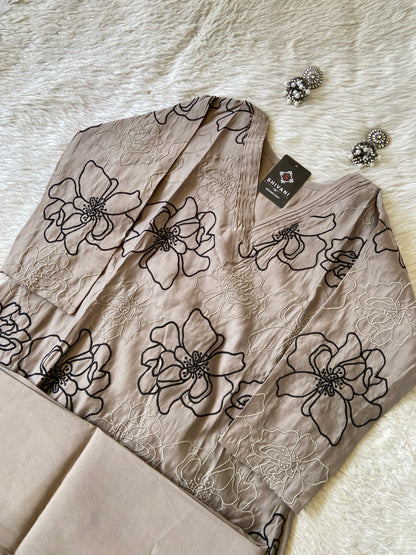 Beige fabric with black floral embroidery on a textured surface