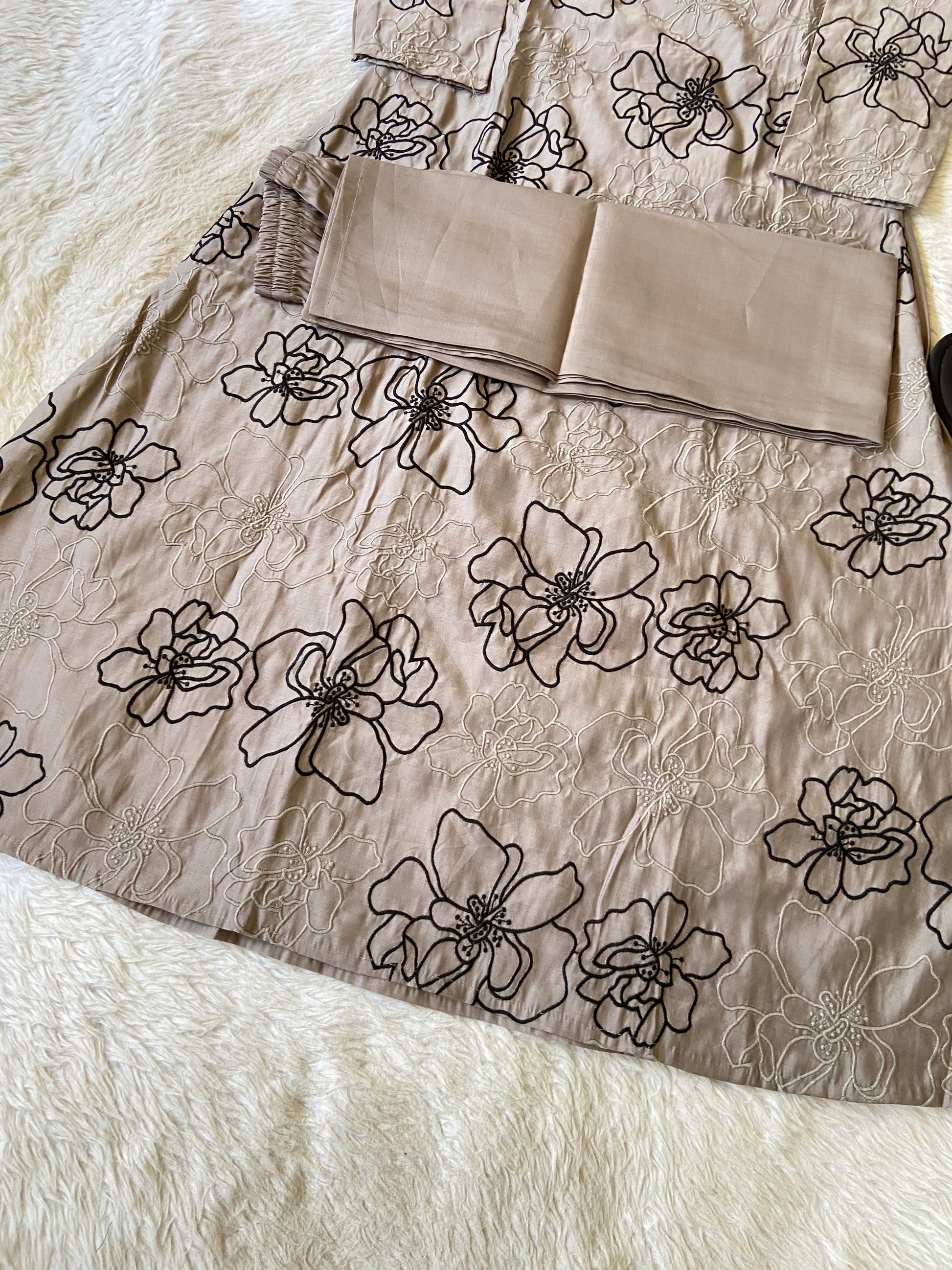 Beige fabric with black floral patterns on a white surface