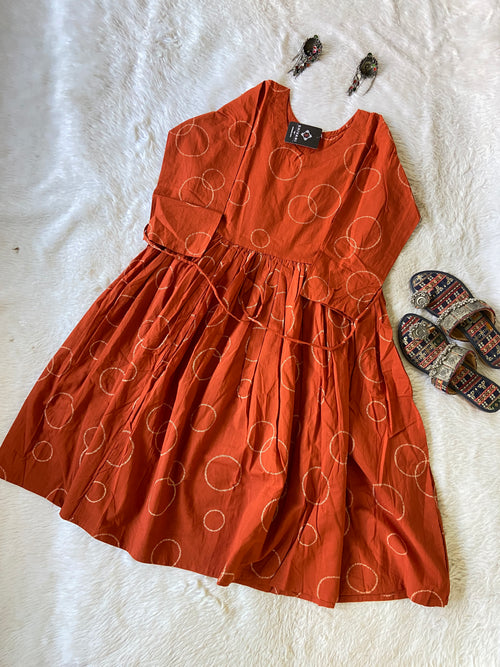 Orange dress with circular pattern on a white surface