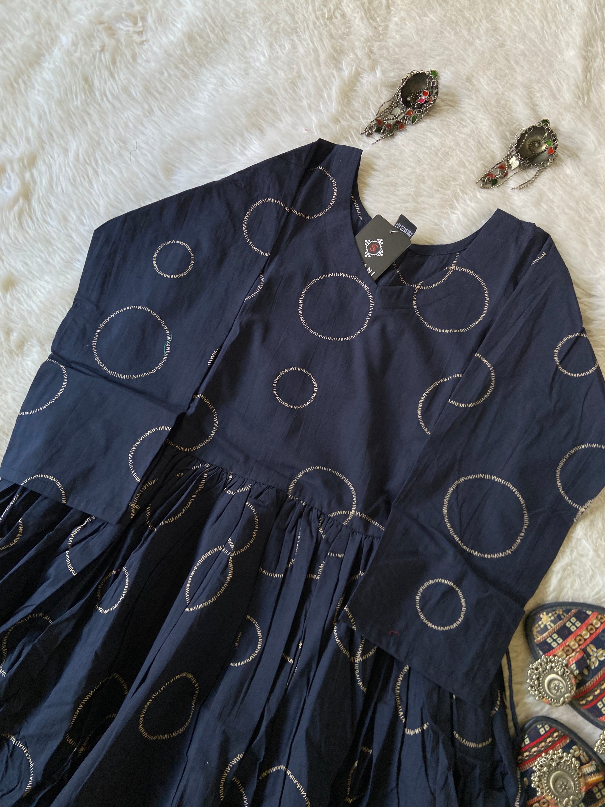 Navy blue dress with white circular patterns on a textured white surface