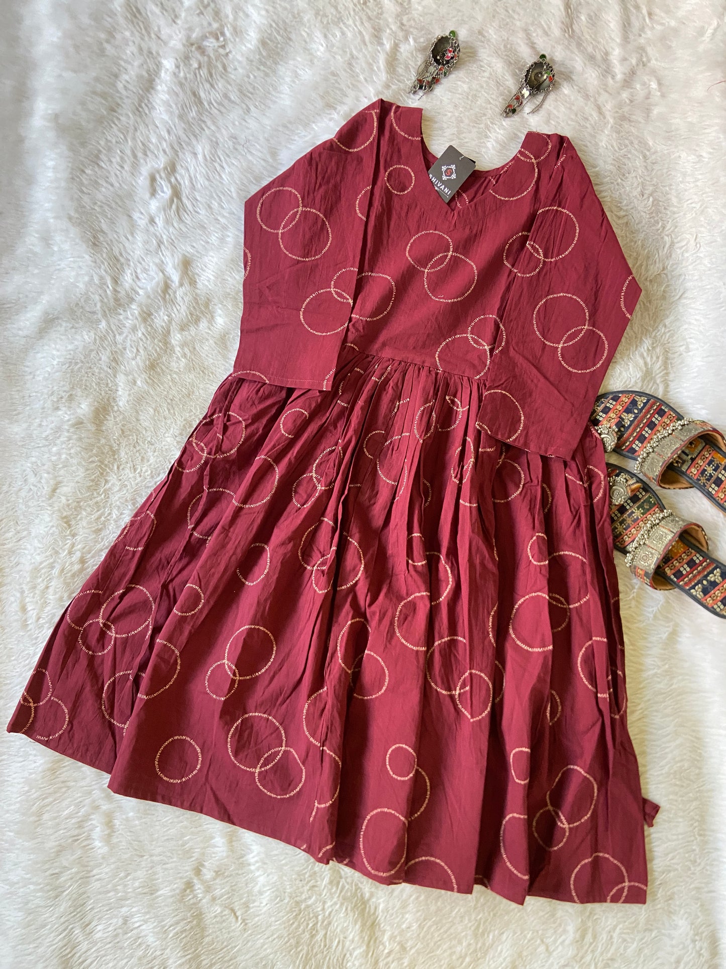 Maroon dress with white circular pattern on a white fur surface