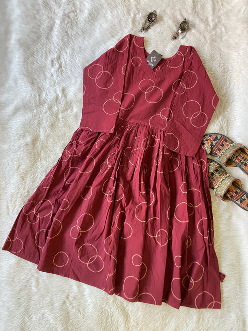 Maroon dress with white circular pattern on a white fur surface
