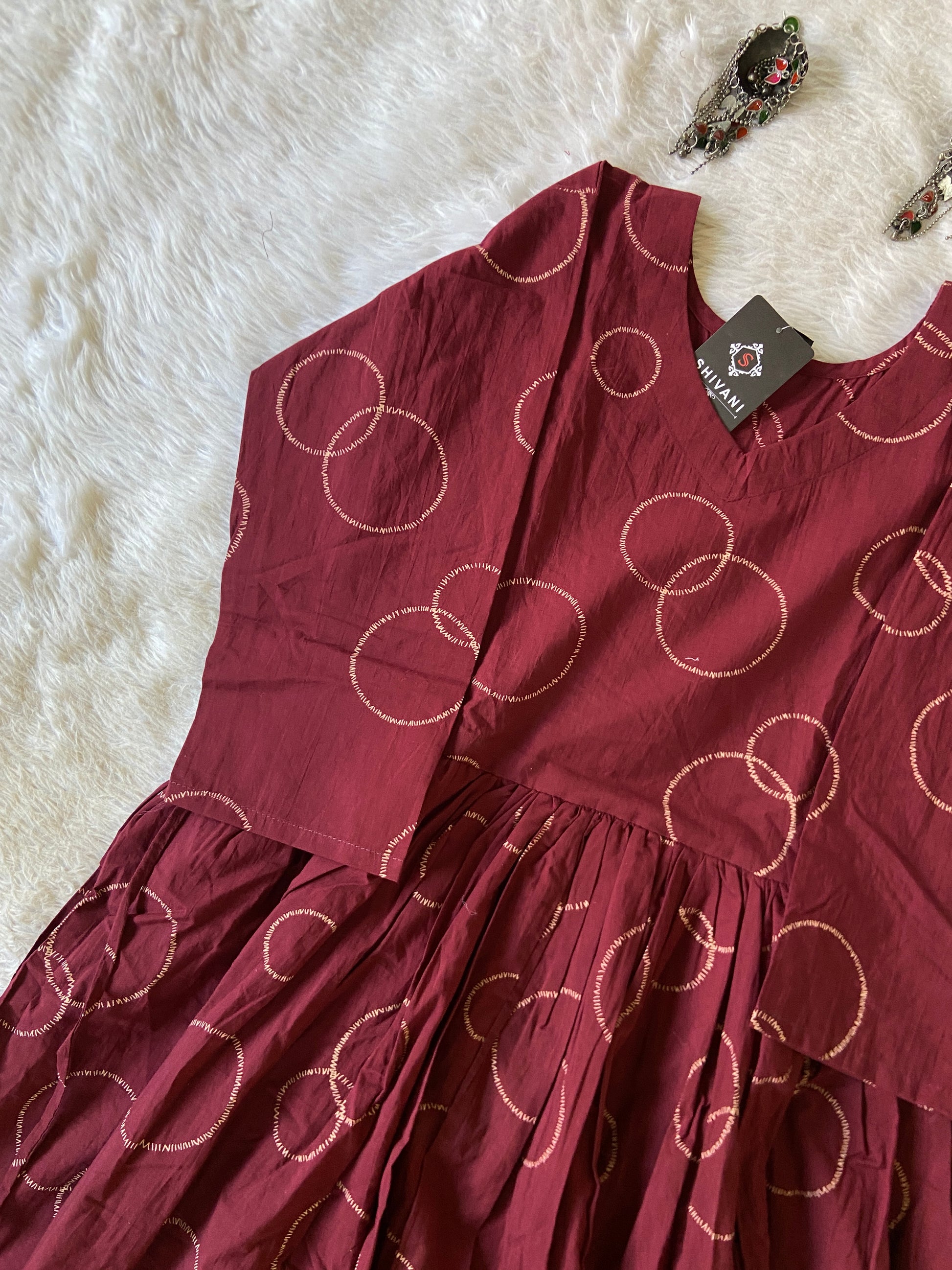 Maroon dress with circular patterns on a white fur surface