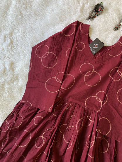 Maroon dress with circular patterns on a white fur surface