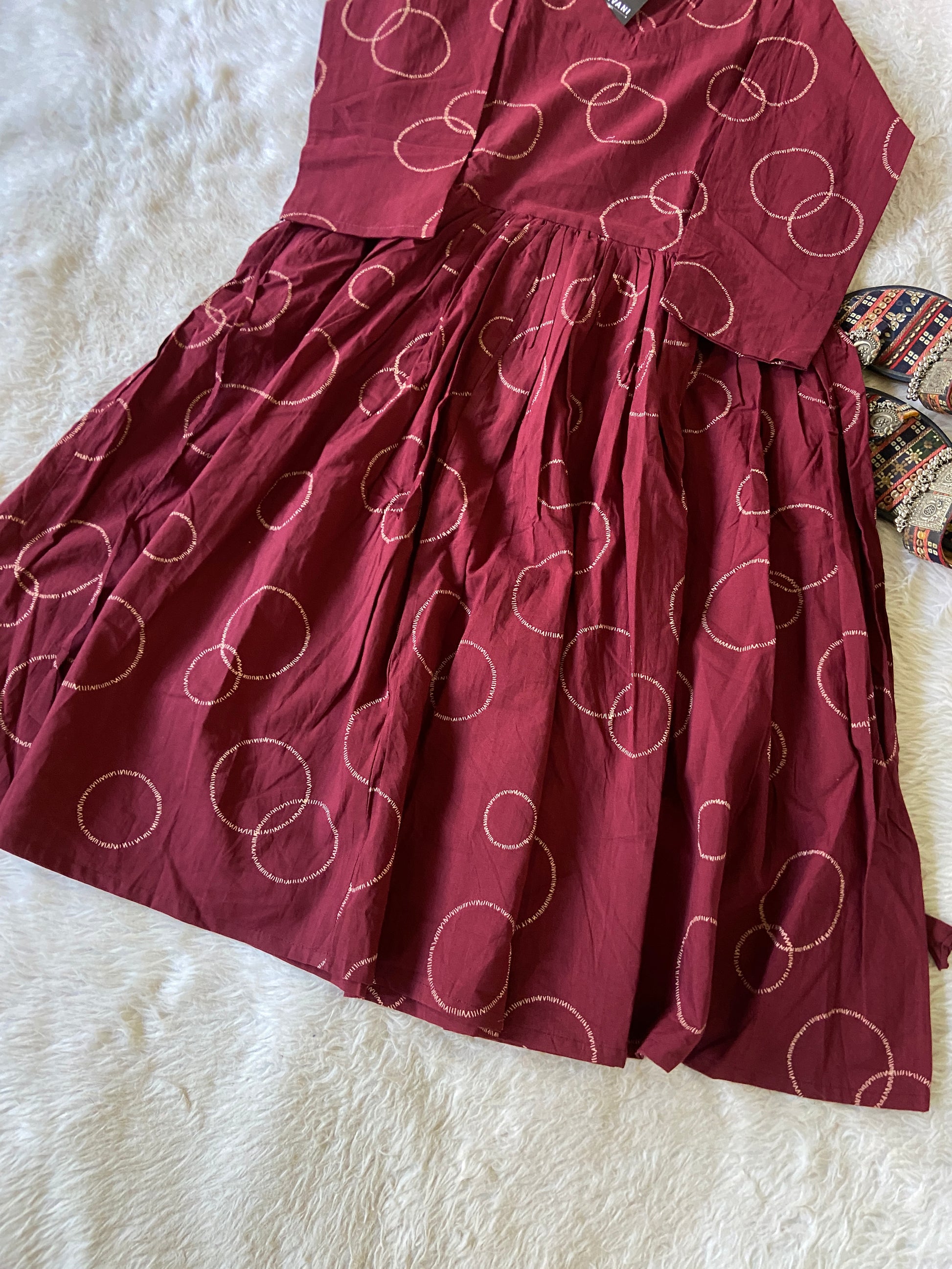 Maroon dress with white circular patterns on a white fur surface