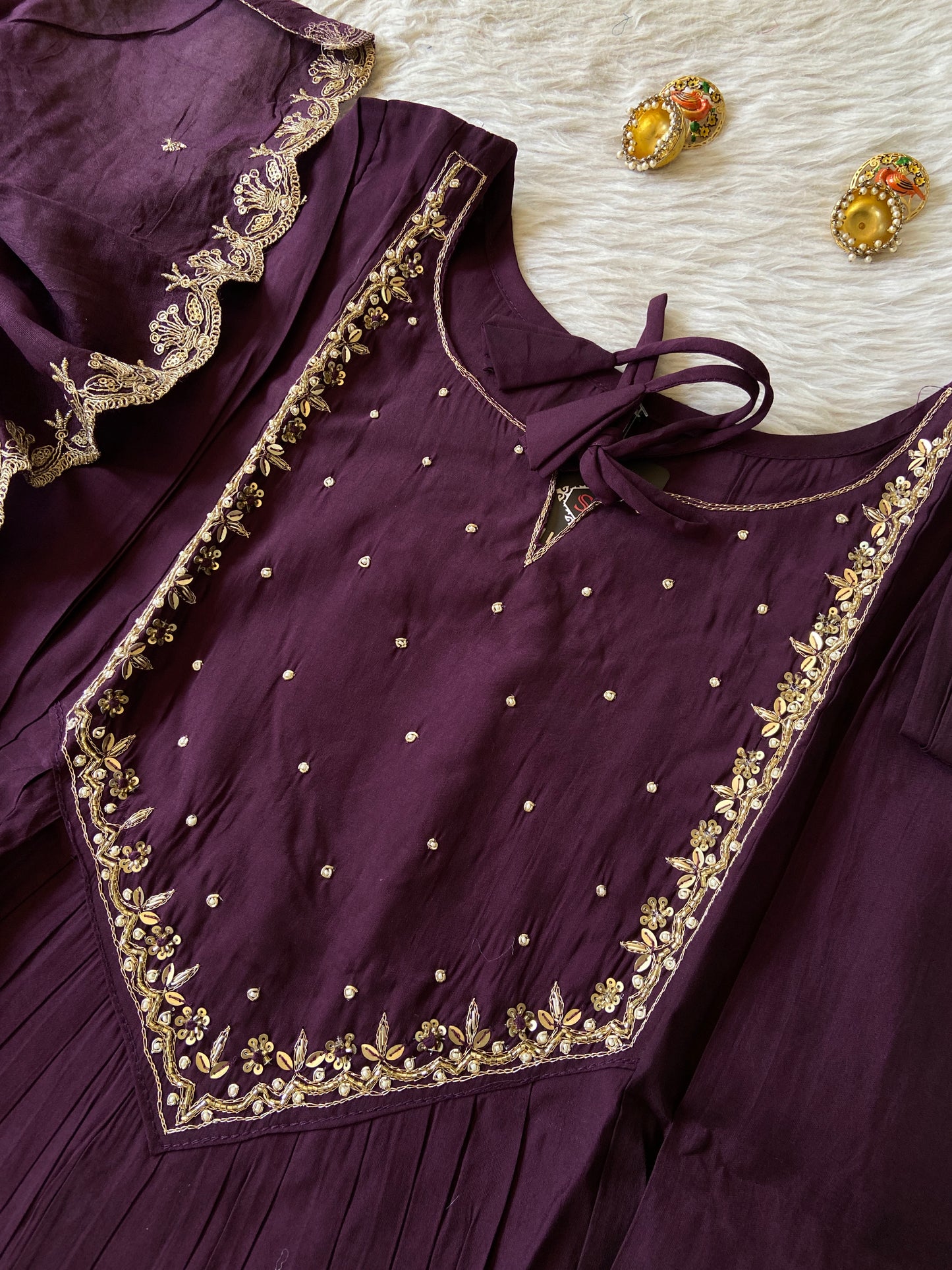 Purple traditional outfit with gold embroidery on a textured surface