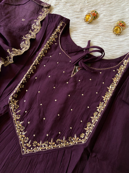 Purple traditional outfit with gold embroidery on a textured surface