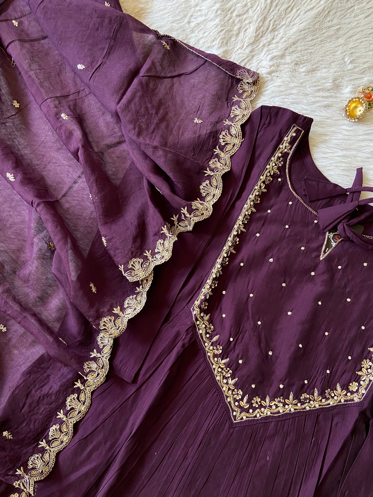 Purple traditional outfit with gold embroidery on a white surface