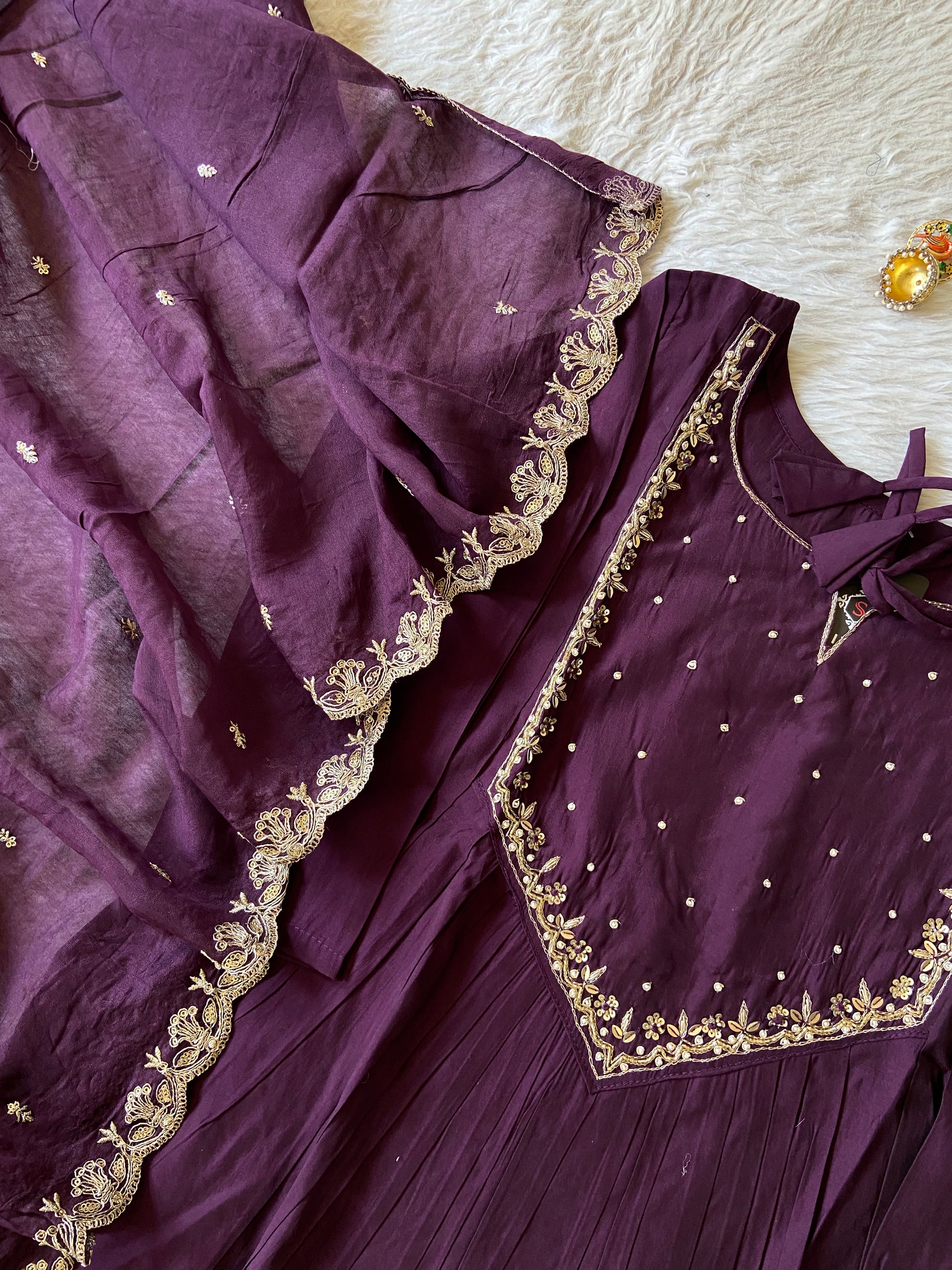 Purple traditional outfit with gold embroidery on a white surface