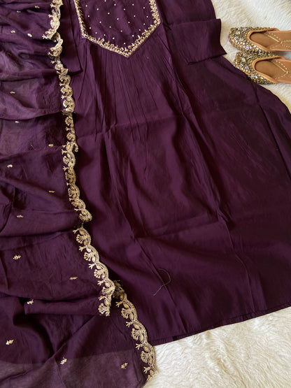 Purple traditional outfit with gold embroidery on a textured surface