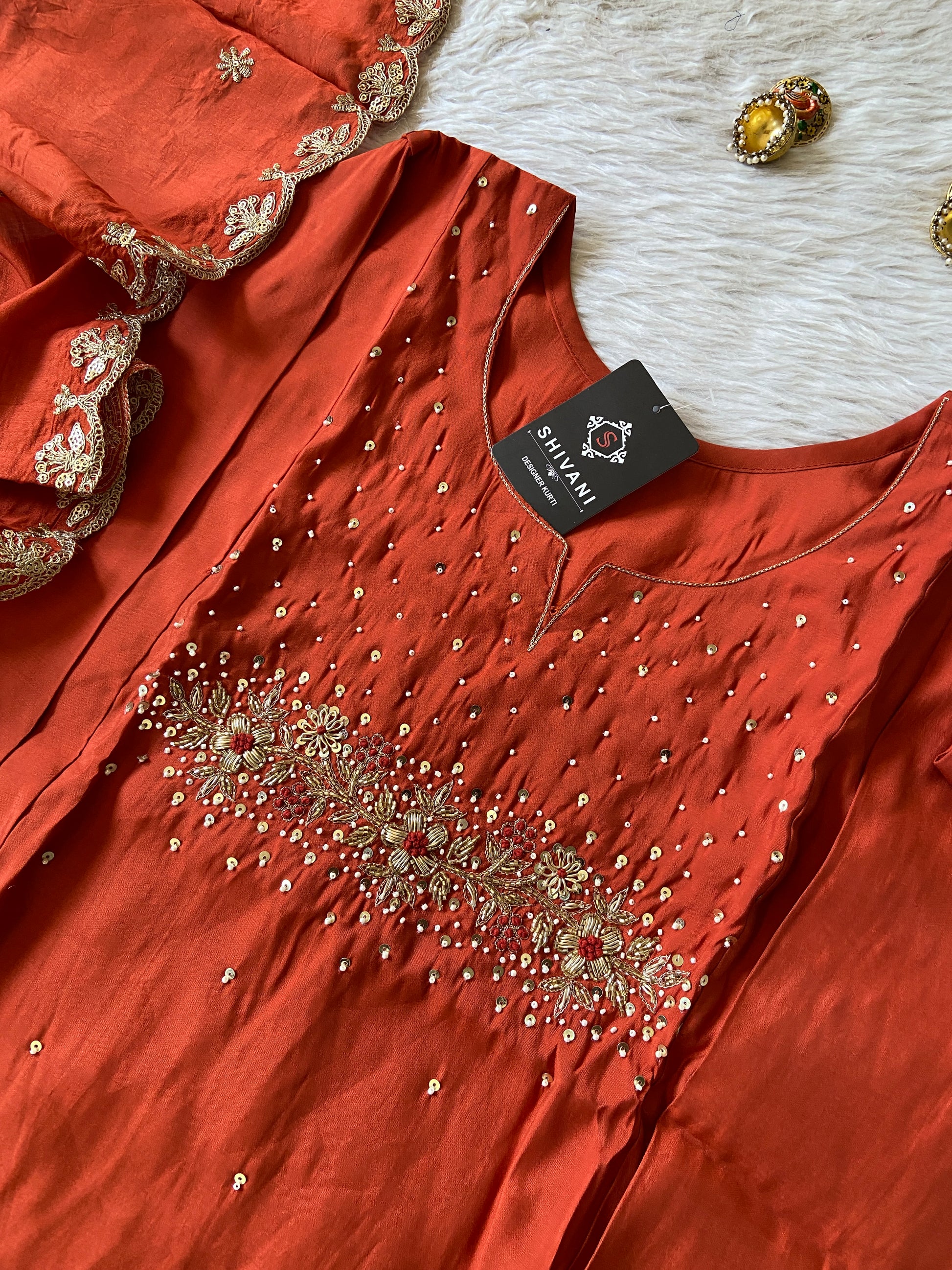 Red embroidered garment with a tag on a textured surface