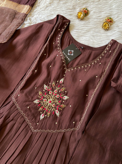 Brown dress with intricate embroidery and a tag on a textured surface