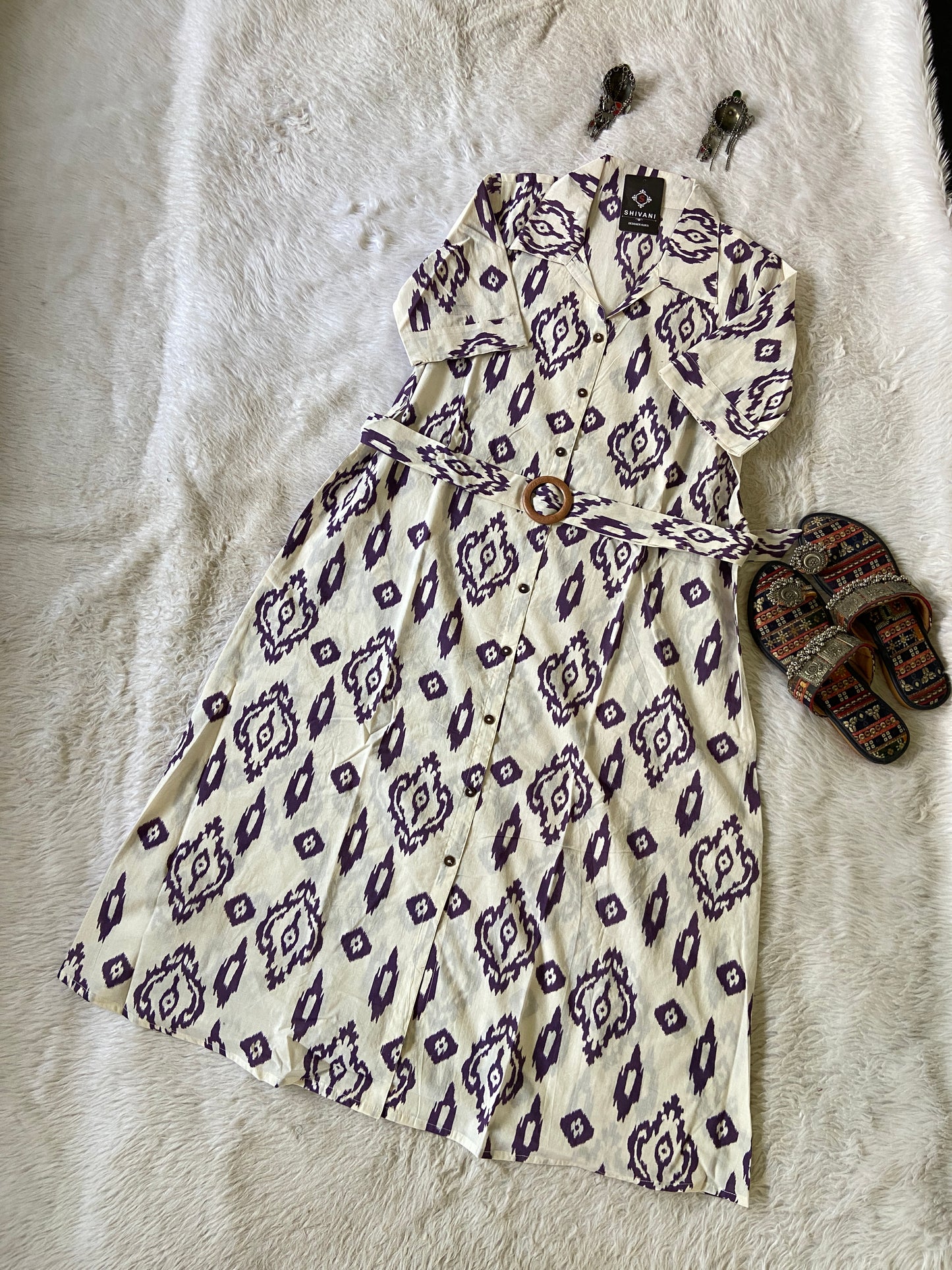 Patterned dress on a textured surface with sandals nearby
