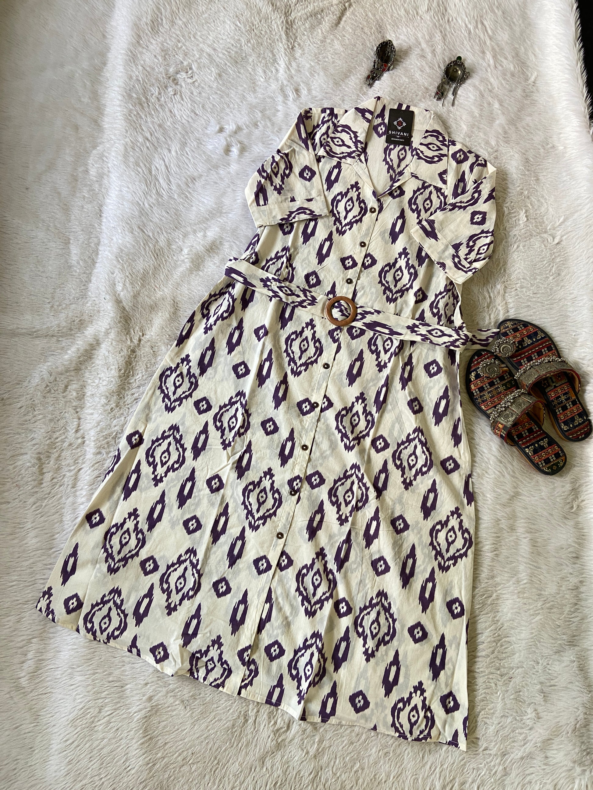 Patterned dress on a textured surface with sandals nearby